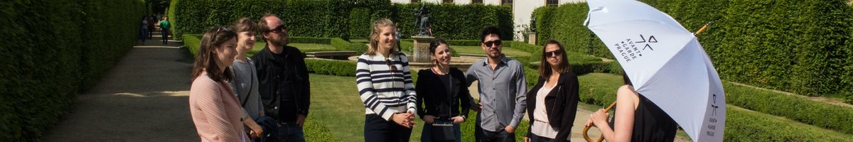 Un guide touristique, un parapluie à la main, s'adresse à sept personnes dans un magnifique jardin