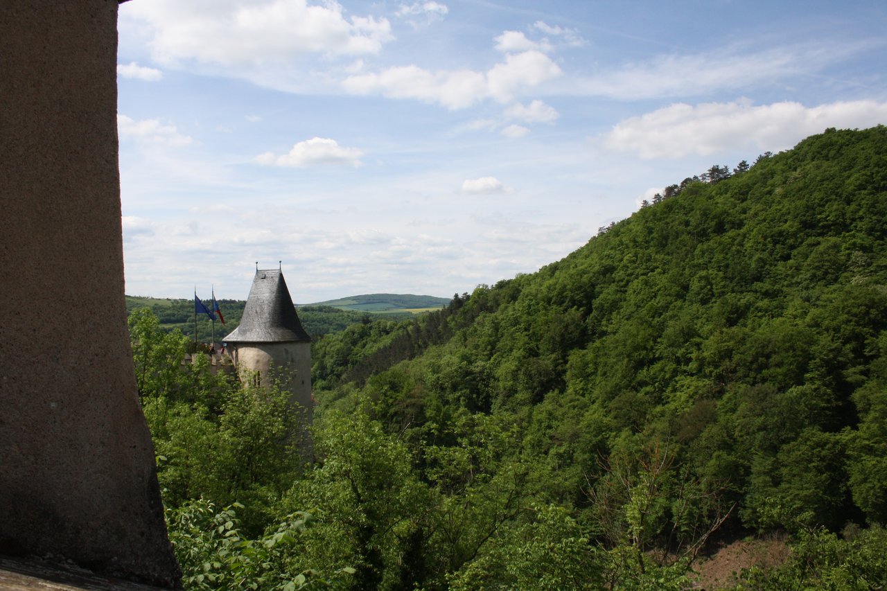 Vue sur la tour du château, avec les drapeaux de l'Europe et de la République tchèque sur le côté, et une foret en arrière-plan