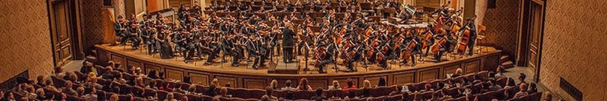 Grande salle de concert avec un orgue géant, il y a beaucoup de siège en forme de demi-cercle et il y a beaucoup de monde