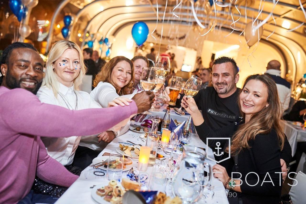 Groupe de personnes qui fête le nouvel an sur un bateau décoré de ballons