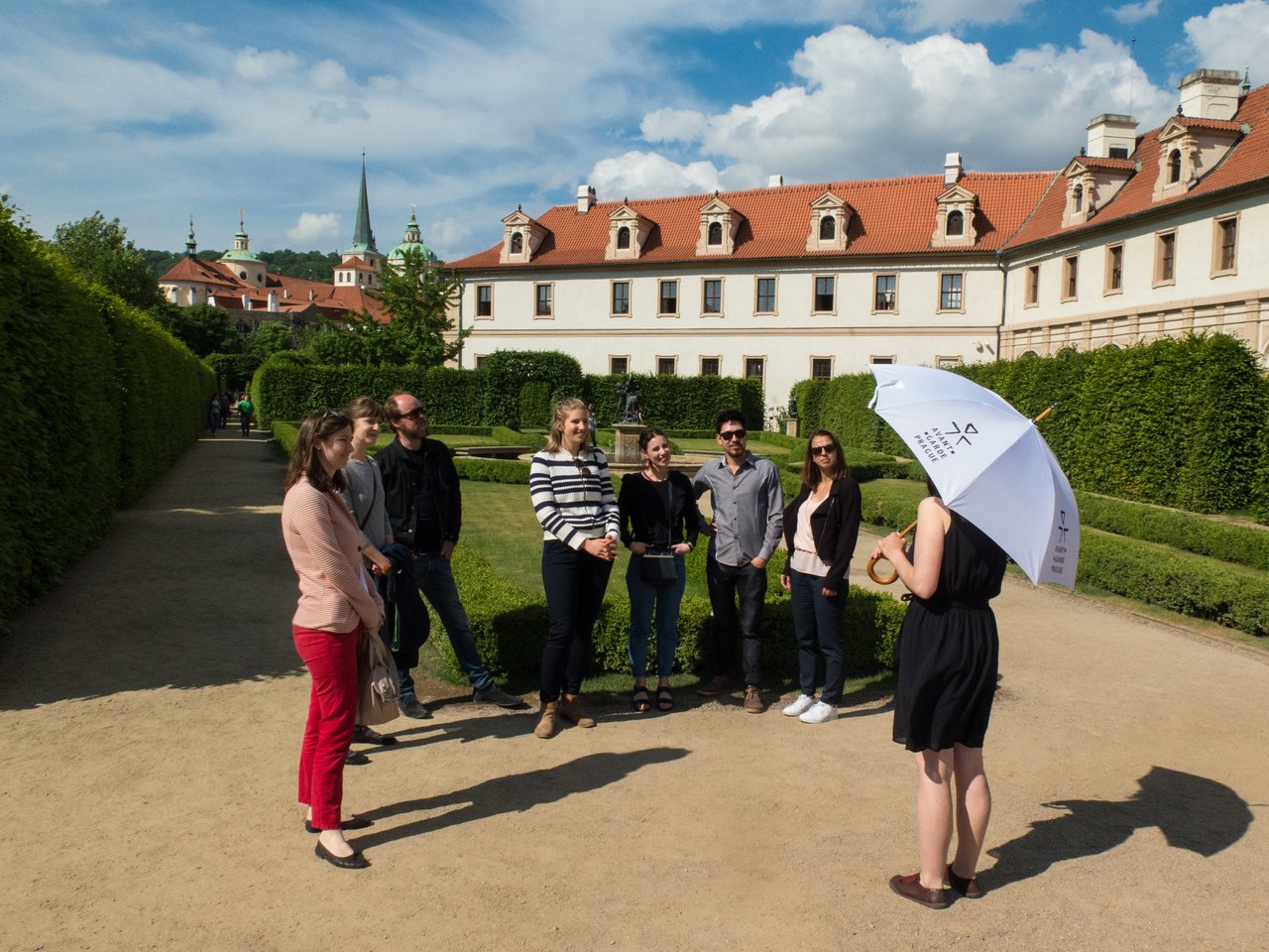 Un guide touristique, un parapluie à la main, s'adresse à sept personnes dans un magnifique jardin