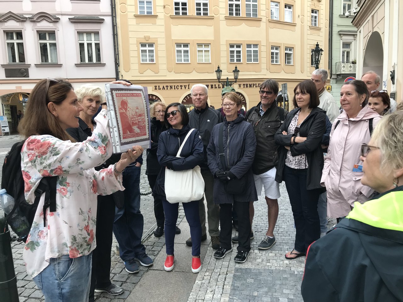 Une femme prend la parole et montre une photo de l'histoire de Prague à un groupe de personnes