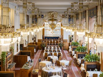 en:Restaurant tables with lots of lit chandeliers; there is a clock in the background; fr:Tables de restaurant avec beaucoup de lustres éclairées, il y a une horloge en fond
