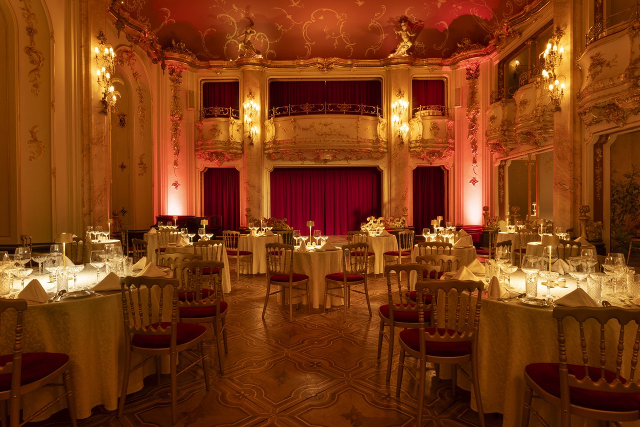 salle de réception à double étage ornée de statues et d'or avec une luminosité douce et tamisée accompagnée d'une scène en fond