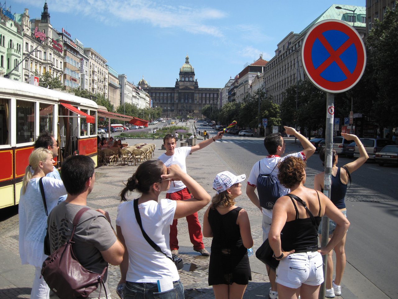 Un guide touristique s'adressant à des touristes sur une grande place, avec un magnifique monument en arrière-plan