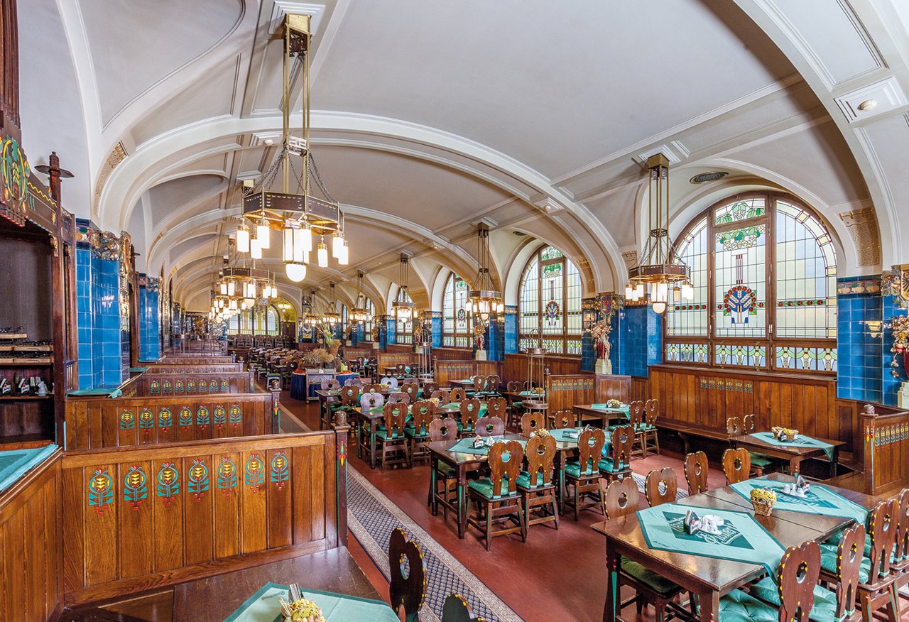 Grande salle avec un toit voûtée et plein de table, les murs sont colorées