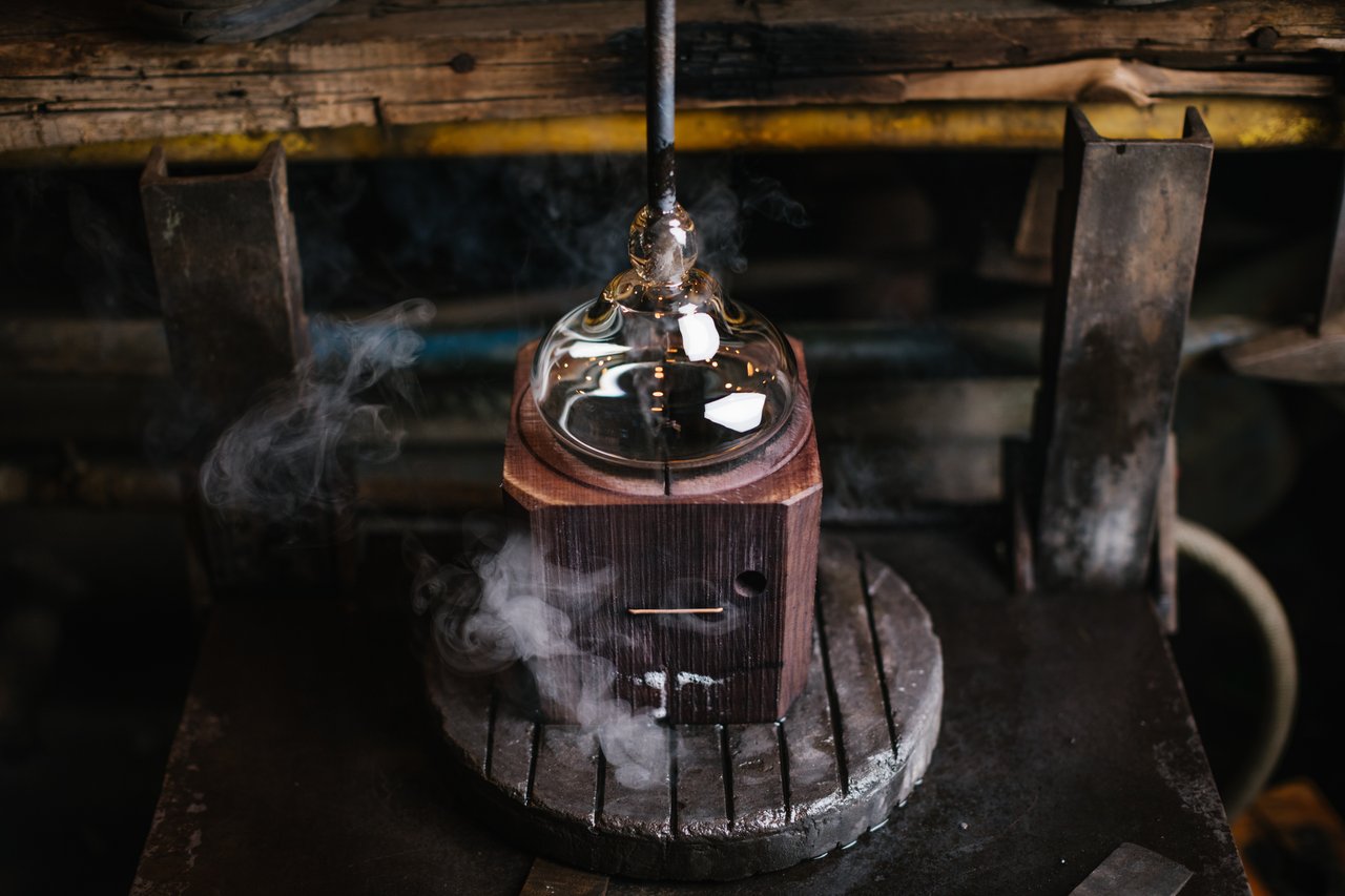 Un morceau de verre fumé, dans lequel on insère un outil en bois pour lui donner la forme souhaitée