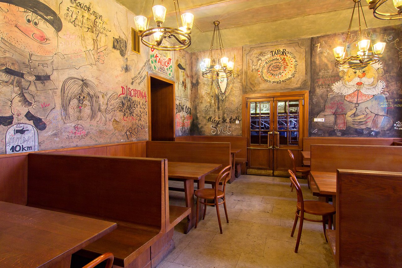 Intérieur d'une brasserie avec des tables en bois et des murs remplis de dessins