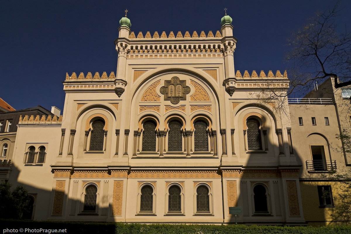 Façade de la Synagogue , avec ses arcs et ses détails géométriques et ses petites coupoles vertes sous un ciel bleu.