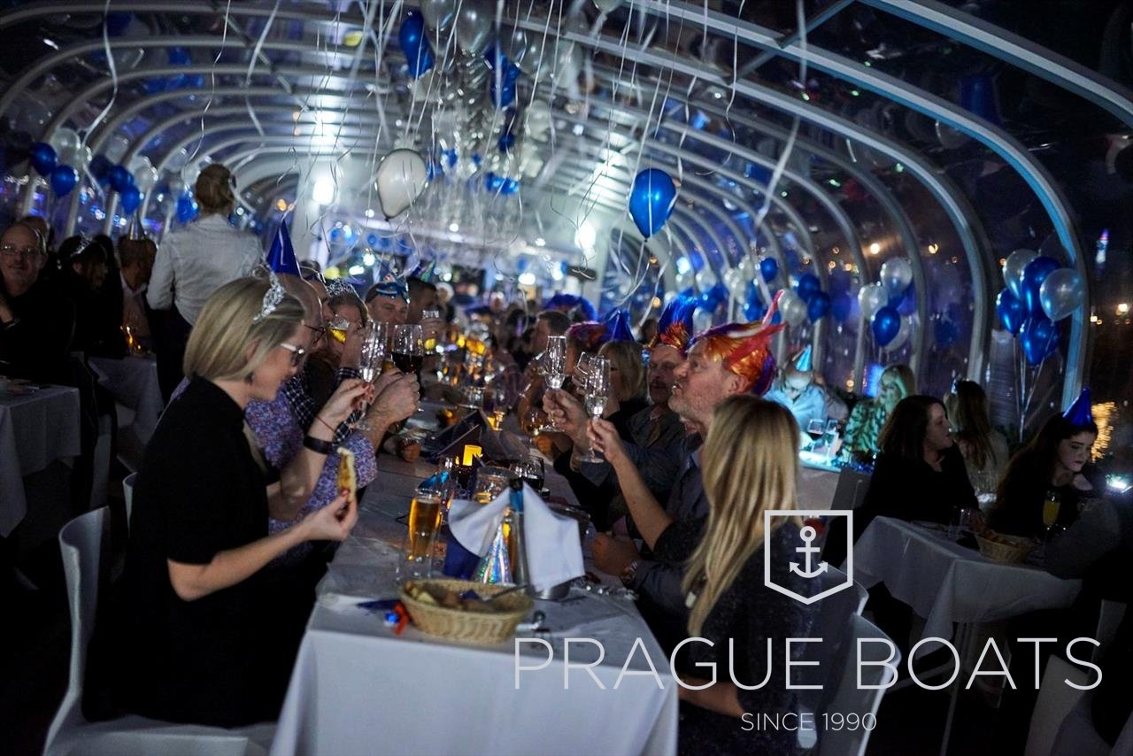 Des personnes qui sont assise à table et qui discute et mangent sur un bateau décoré