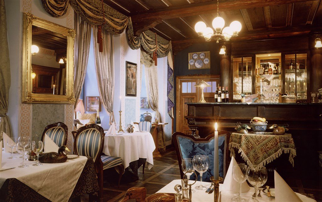 Salle remplie de tables de restaurant avec des bougies et un lustre au milieu