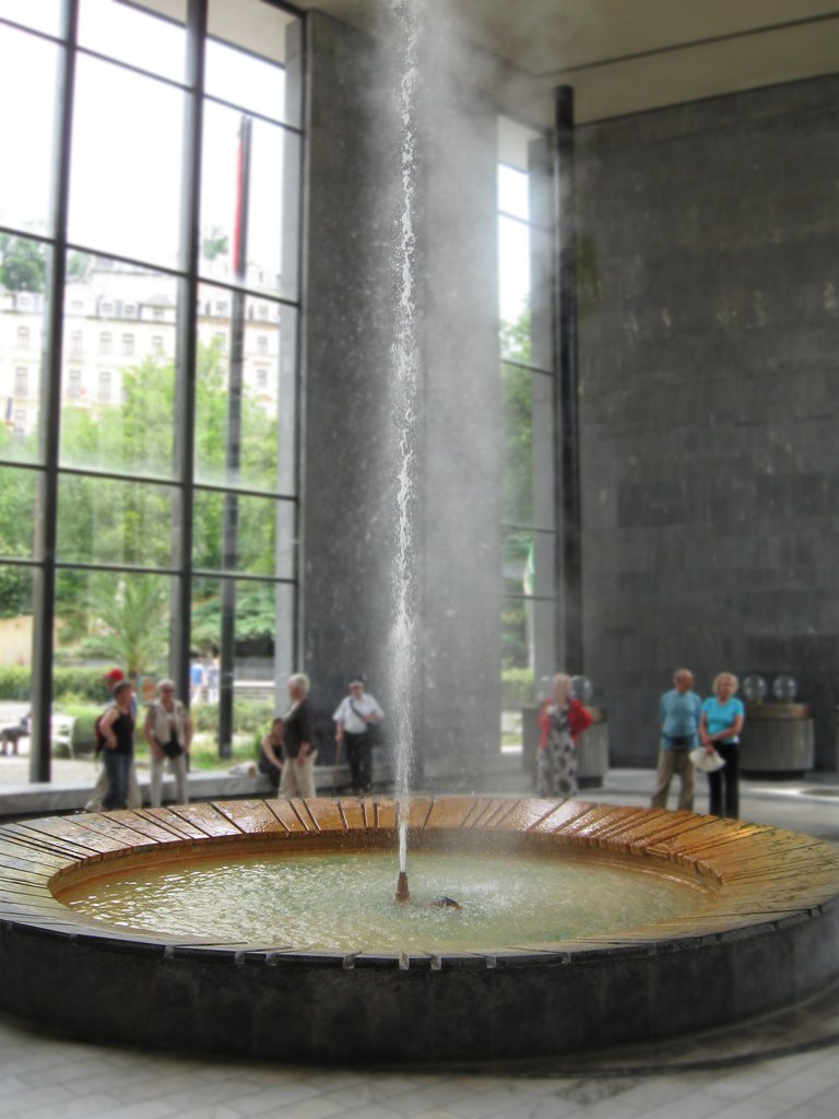 Une fontaine circulaire d'où jaillit un jet d'eau, accompagné de fumée s'élevant de l'eau