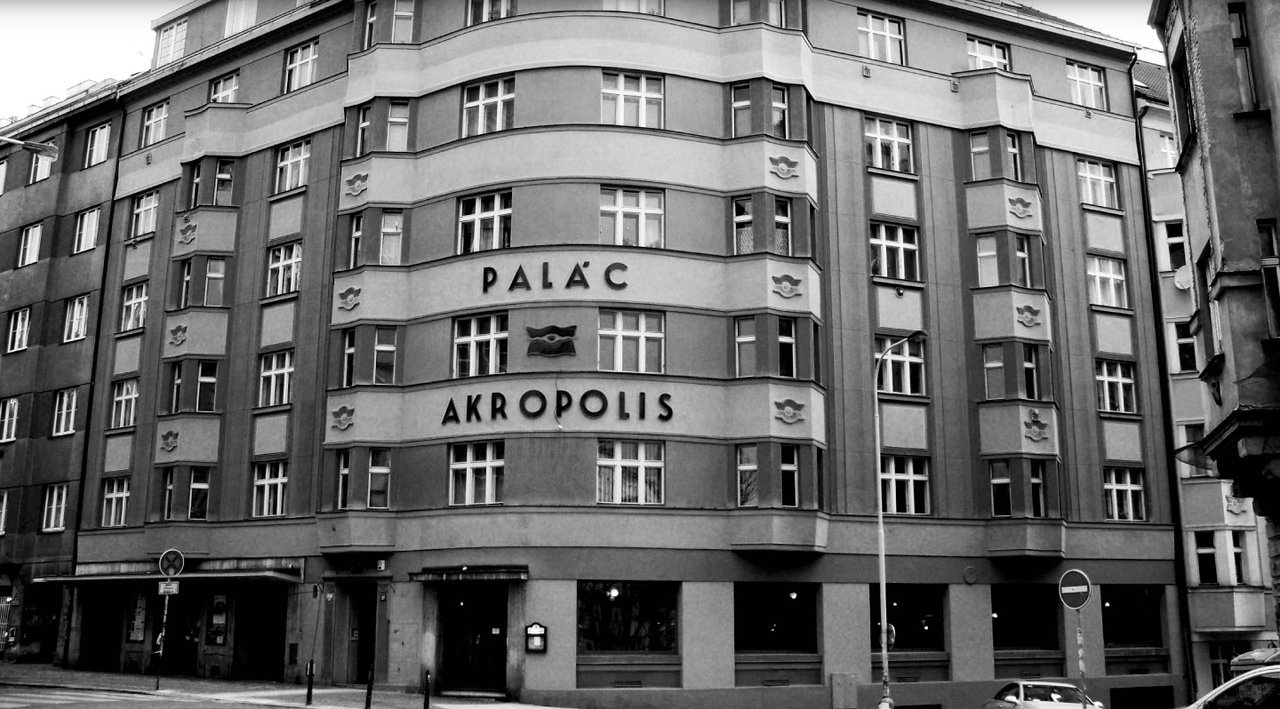 Une façade de grand bâtiment d'angle en noir et blanc, avec de nombreuses fenêtres alignées sur plusieurs étages