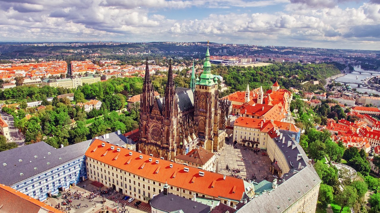 Vue aérienne avec la cathédrale gothique du château de Prague, entourée de grands bâtiments aux tuiles oranges vif