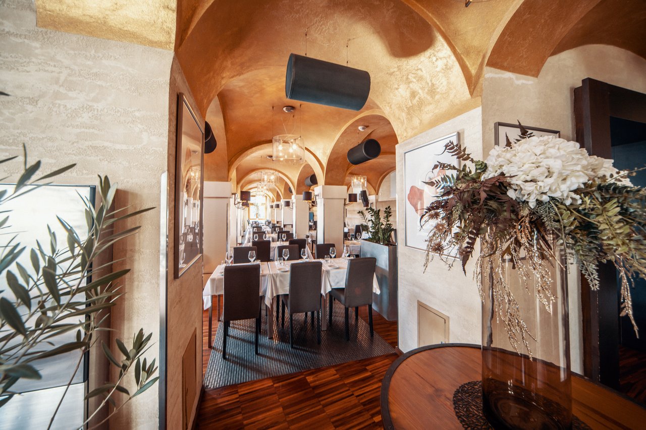 Salle de restaurant avec un plafond voûtée et un pot avec des fleurs sur une table