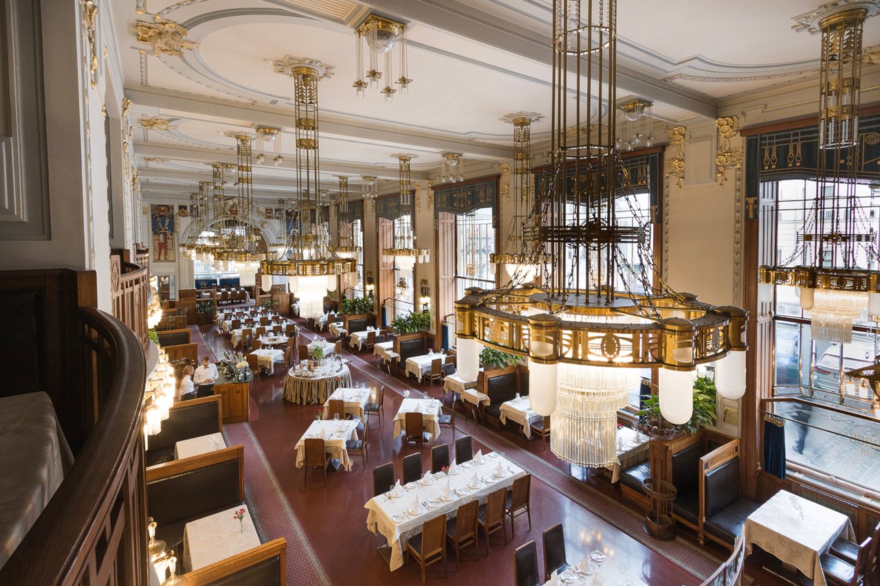 Grande salle à manger avec beaucoup de lustre suspendus il y a des dorures sur les murs