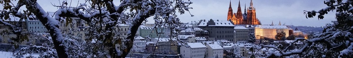 Vue sur la ville enneigée, avec en arrière-plan le château de Prague illuminé