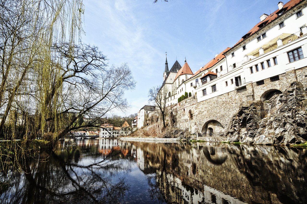 Une forteresse médiévale en pierre aux murs blancs et au toit rouge, surplombant une rivière