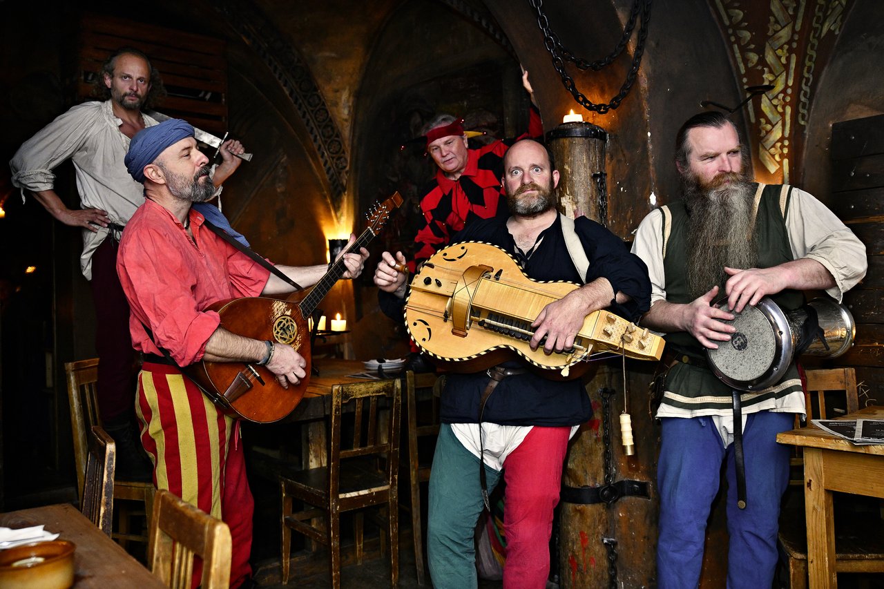 Cinq musiciens en tenue médiévale qui jouent de l'instrument