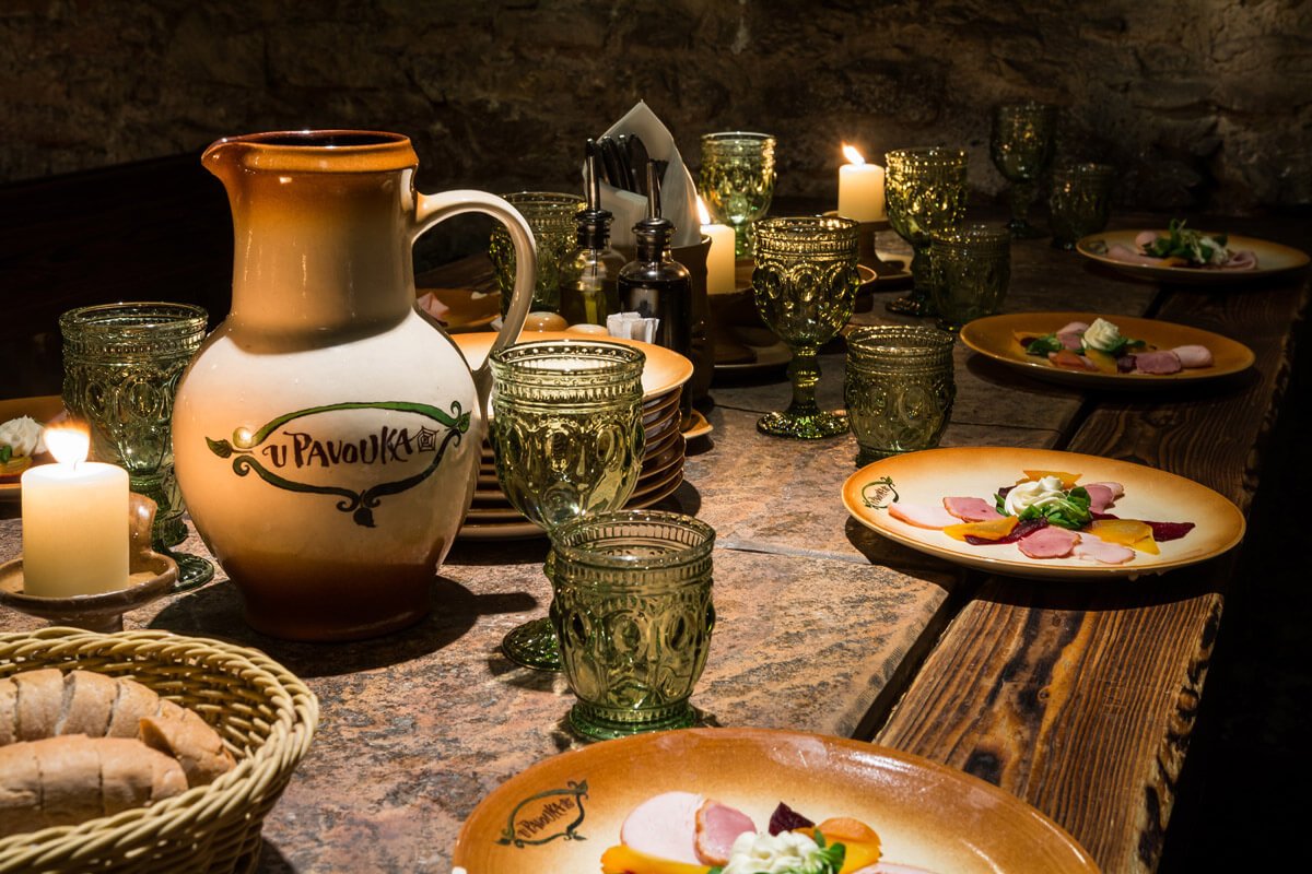 Table avec des verres médiévaux et des assiettes remplie de nourritures avec une carafe au centre