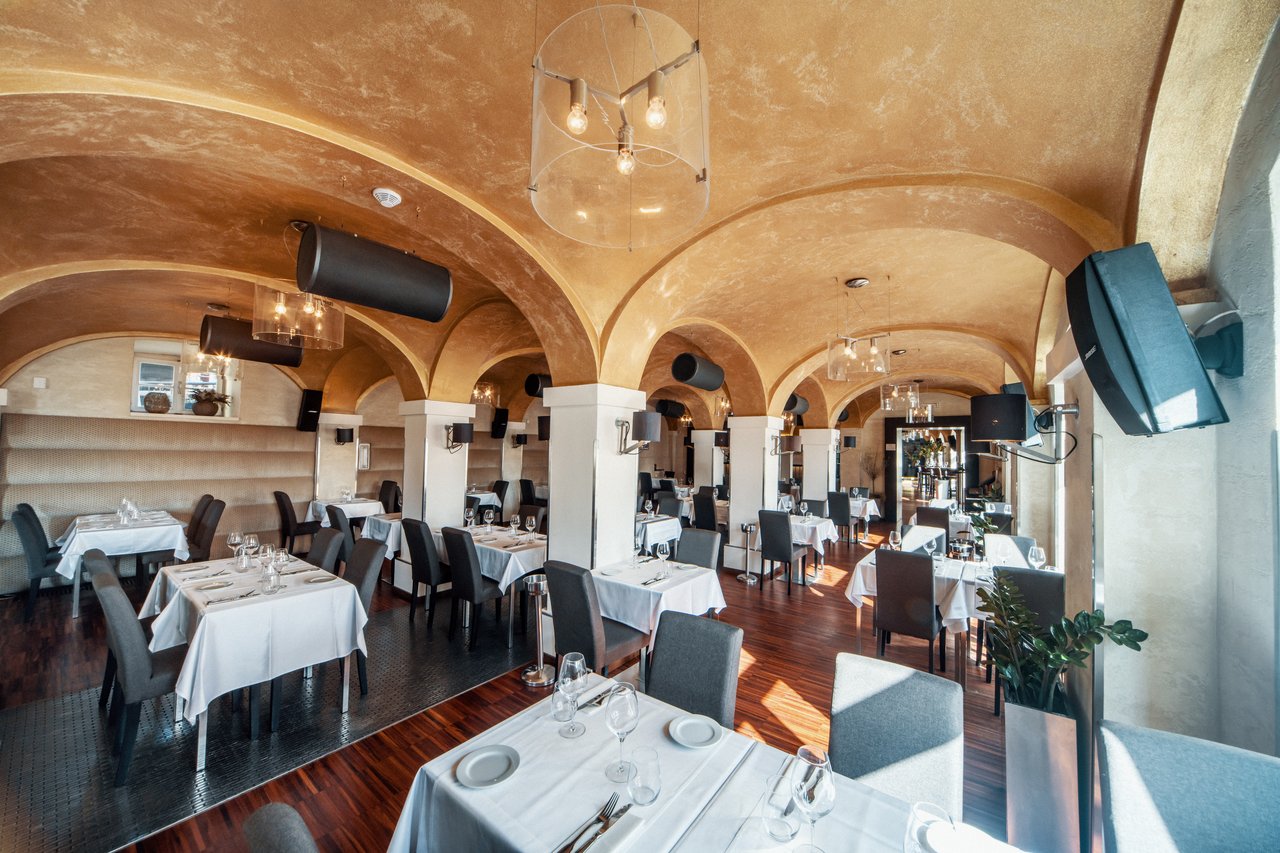 Salle de restaurant avec un plafond voûtée et plusieurs enceintes accrochées à plusieurs endroits