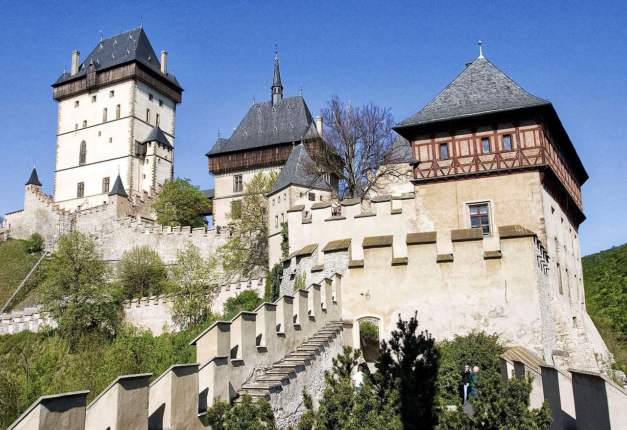 Une forteresse en pierre blanche, surmontée de hauts toits pointus en entourée de remparts