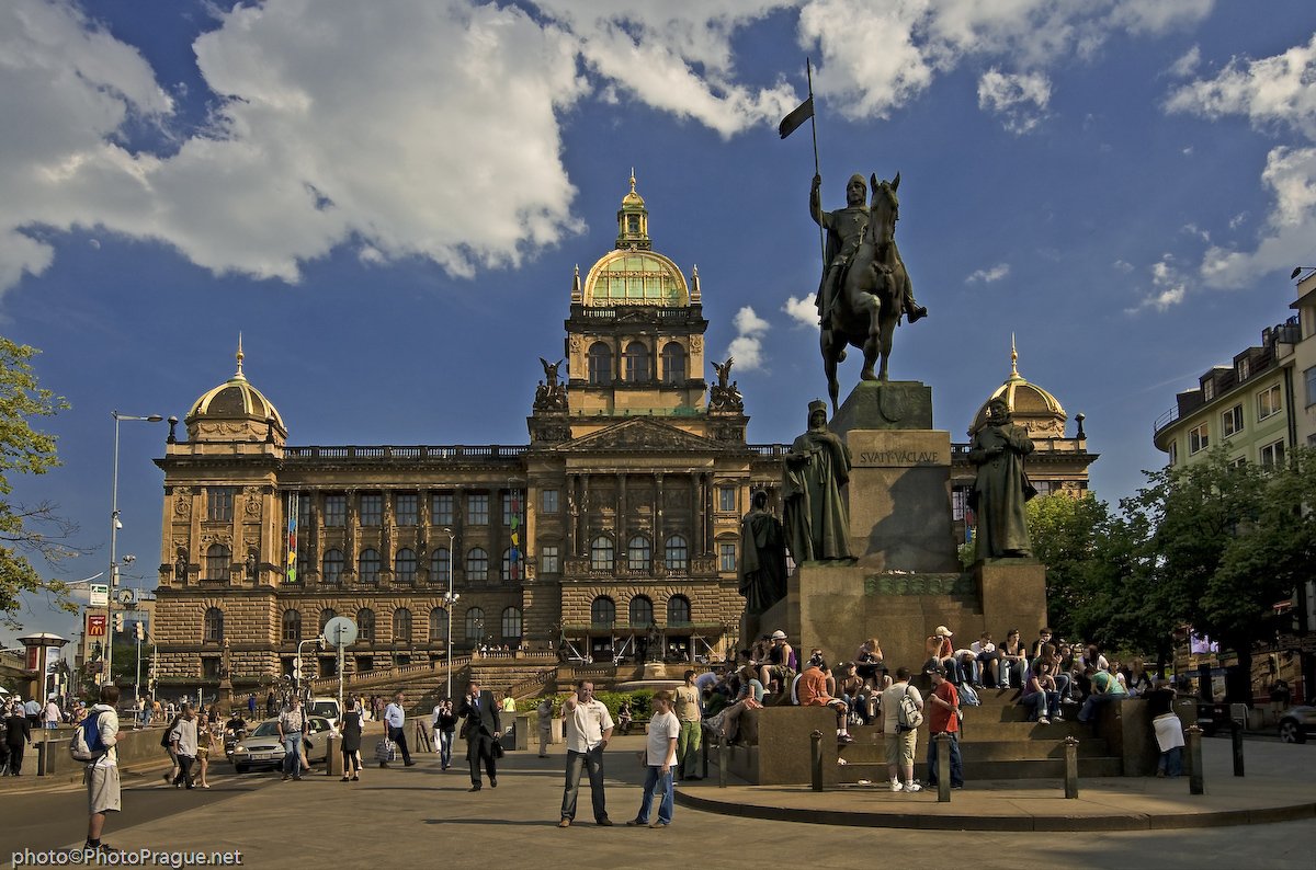 Une grande statue en bronze d'un homme à cheval  sur une place animée, devant un immense palais en pierre doté d'un dôme doré