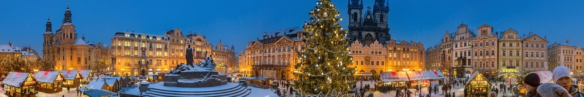 Un grand marché de Noël avec un immense sapin décoré en son centre, la nuit tombe et la ville s'illumine