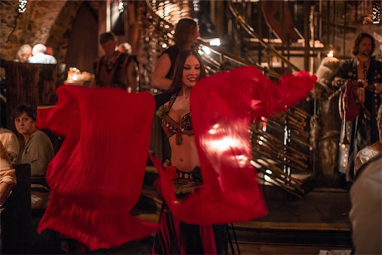 Femme en costume médiéval qui danse avec des foulards rouges