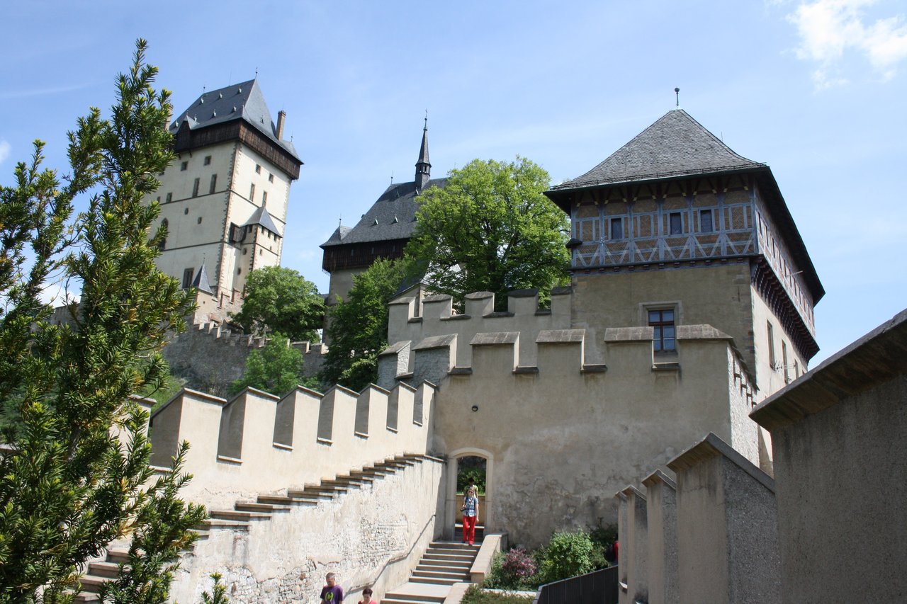 Remparts fortifiés et les tours médiévales du château  entourés de végétation sous un ciel bleu.
